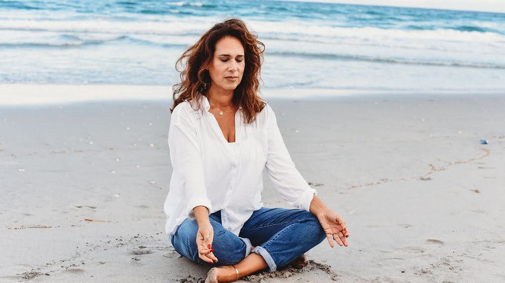 Claudia Rotman meditating on the beach